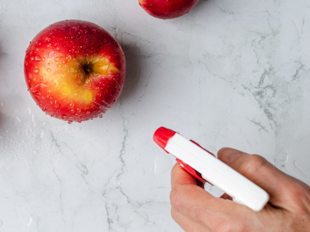 Apple On Marble Countertop Being Sprayed with Squirt Bottle