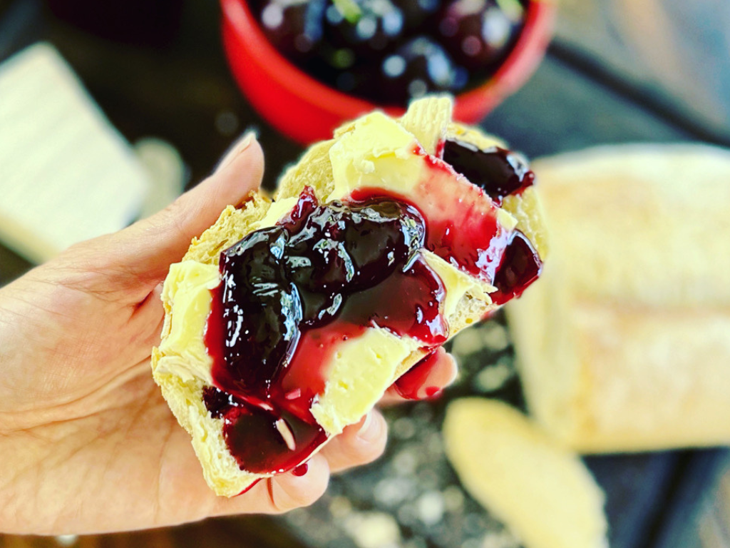 Sweet Red Cherry Refrigerator Jam on Bread with a Hand Holding it and a Blurred Out Background