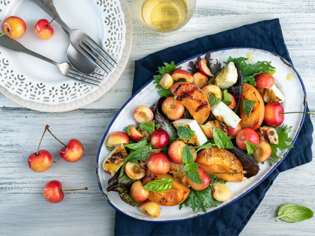 Grilled Halloumi and Stone Fruit Salad with Cherries on an Oval Plate on a Cloth