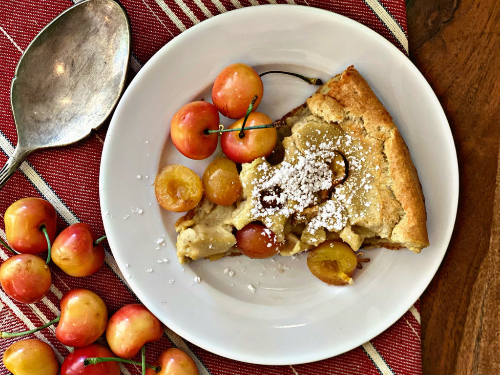 A Slice of Rainier Cherry Dutch Baby, with Pumpkin Spice & Oat Milk on a Plate with a Spoon