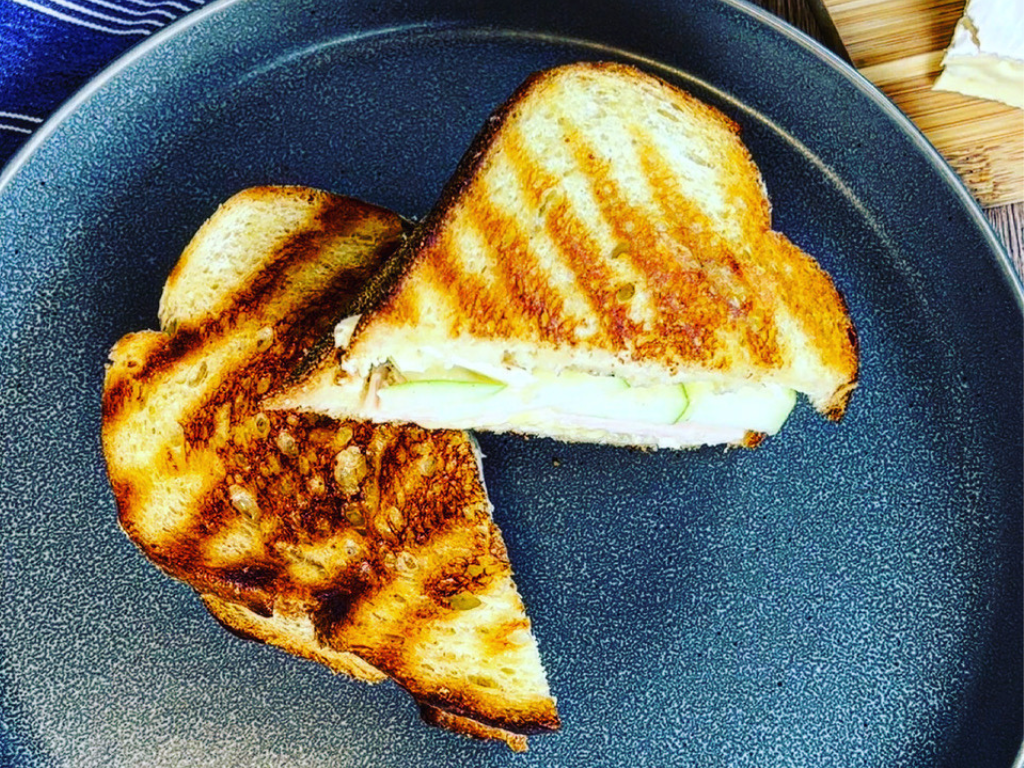 Granny Smith Apple, Turkey, and Brie Grilled Cheese Cut in Half on a Plate